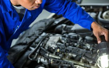 Attentive mechanic examining car at repair garage